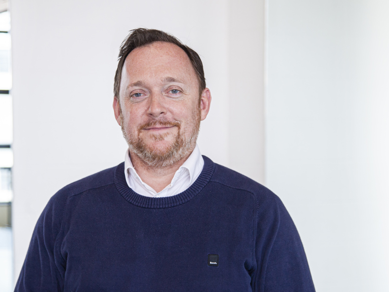 Headshot of Andrew Hurst. White male with light hair and beard smiling at camera, wearing blue jumper  Headshot of Andrew Hurst. White male with light hair and beard smiling at camera, wearing blue jumper