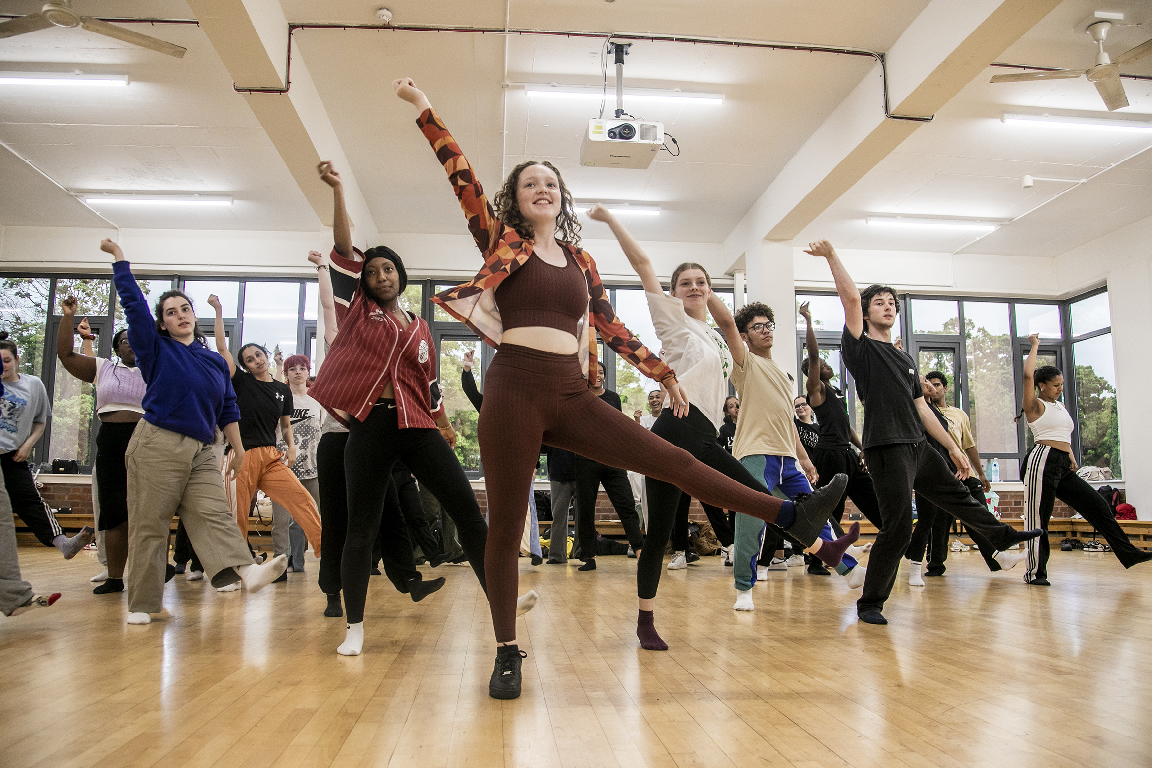 young dancers rehearing in dance studio. All with one one leg up and one arm straight leaning to the left. Mix of male and female dancers with different ethnicities. Wearing comfy casual clothes young dancers rehearing in dance studio. All with one one leg up and one arm straight leaning to the left. Mix of male and female dancers with different ethnicities. Wearing comfy casual clothes