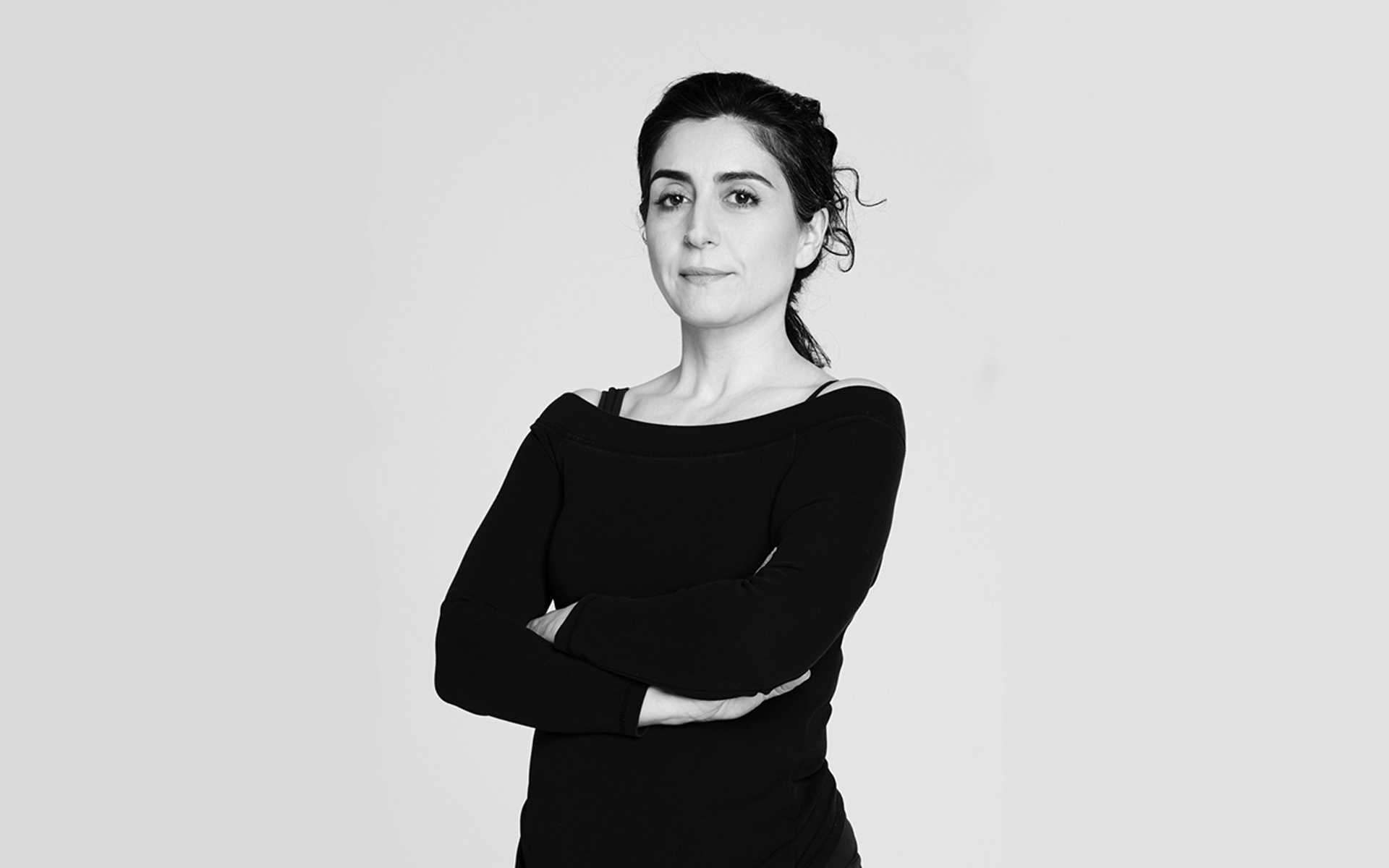 black and white headshot of Xenia Aidonopoulou. Female dancer with arms crossed black and white headshot of Xenia Aidonopoulou. Female dancer with arms crossed