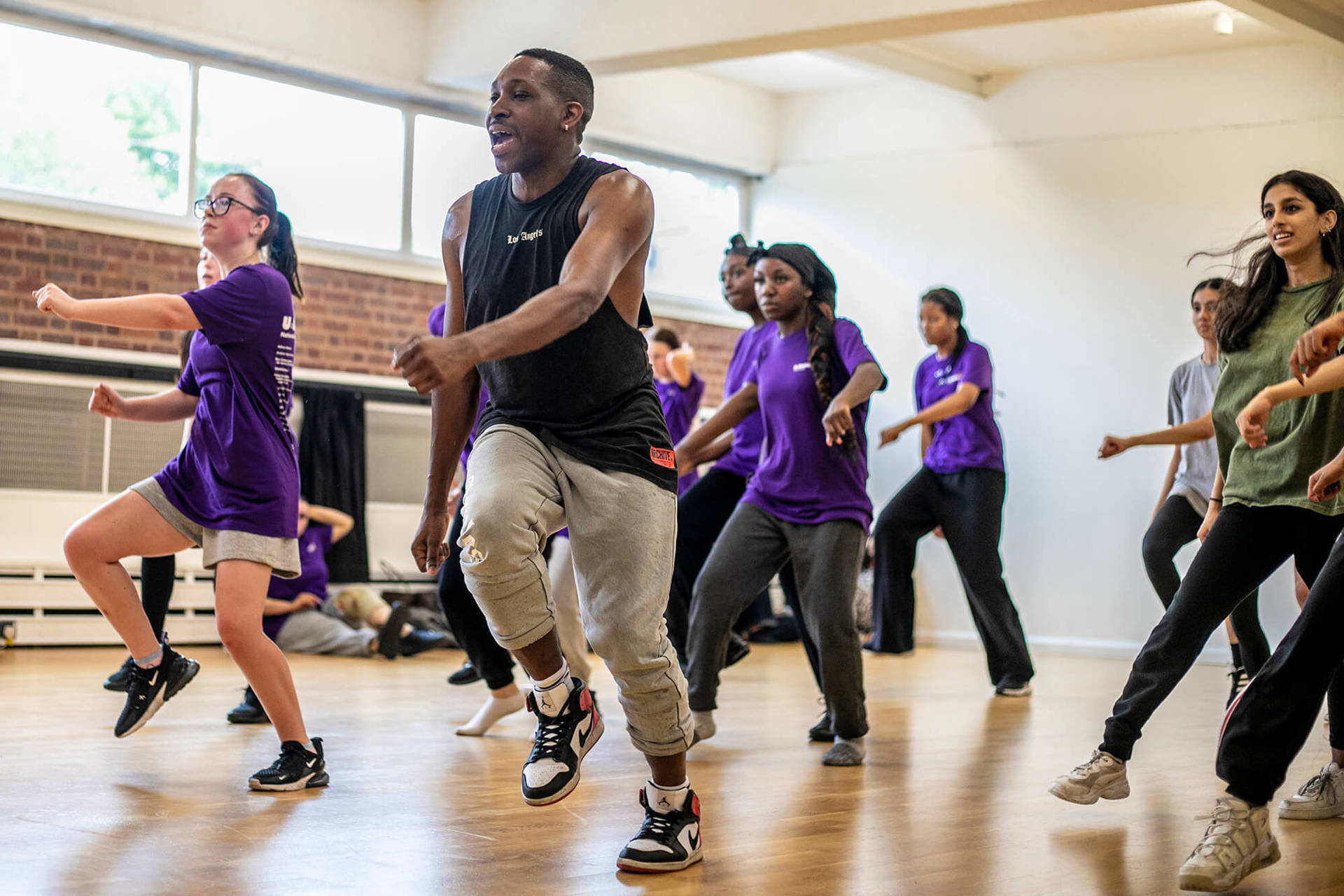 black male dancer  teaching a group of young people to dance. all in a running man position wearing athletic clothing in a dance studio.  black male dancer  teaching a group of young people to dance. all in a running man position wearing athletic clothing in a dance studio.