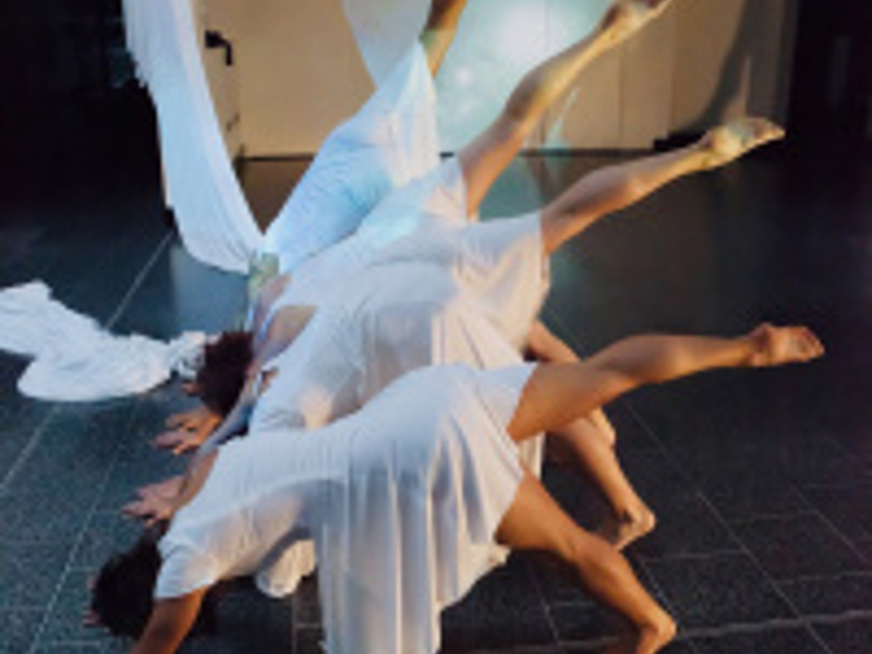 Four dancers starting a cartwheel wearing white dresses