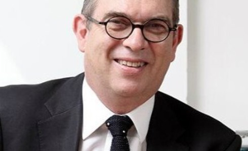 Headshot Anthony Bowne. White male smiling with circular glasses. Short grey hair, wearing a black suit, white shirt, and black tie.