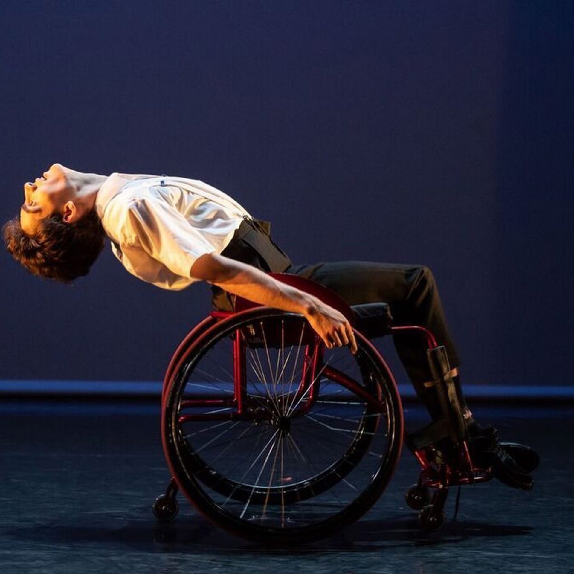 white male in a wheel chair bending backwards on a stage