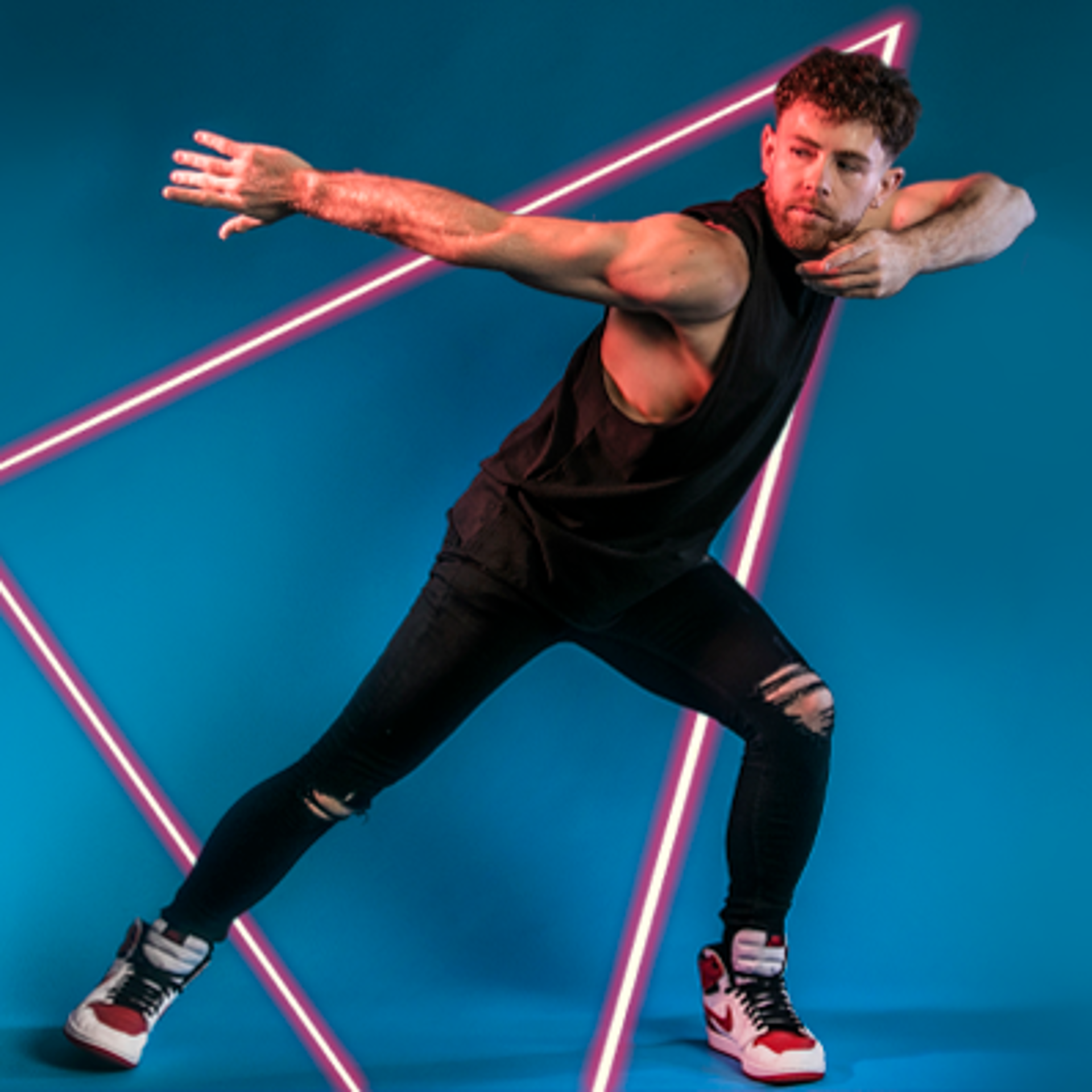 white male dancer lunging to the right with arms pointed to the left. Black outfit and white trainers. On blue studio background. white male dancer lunging to the right with arms pointed to the left. Black outfit and white trainers. On blue studio background.