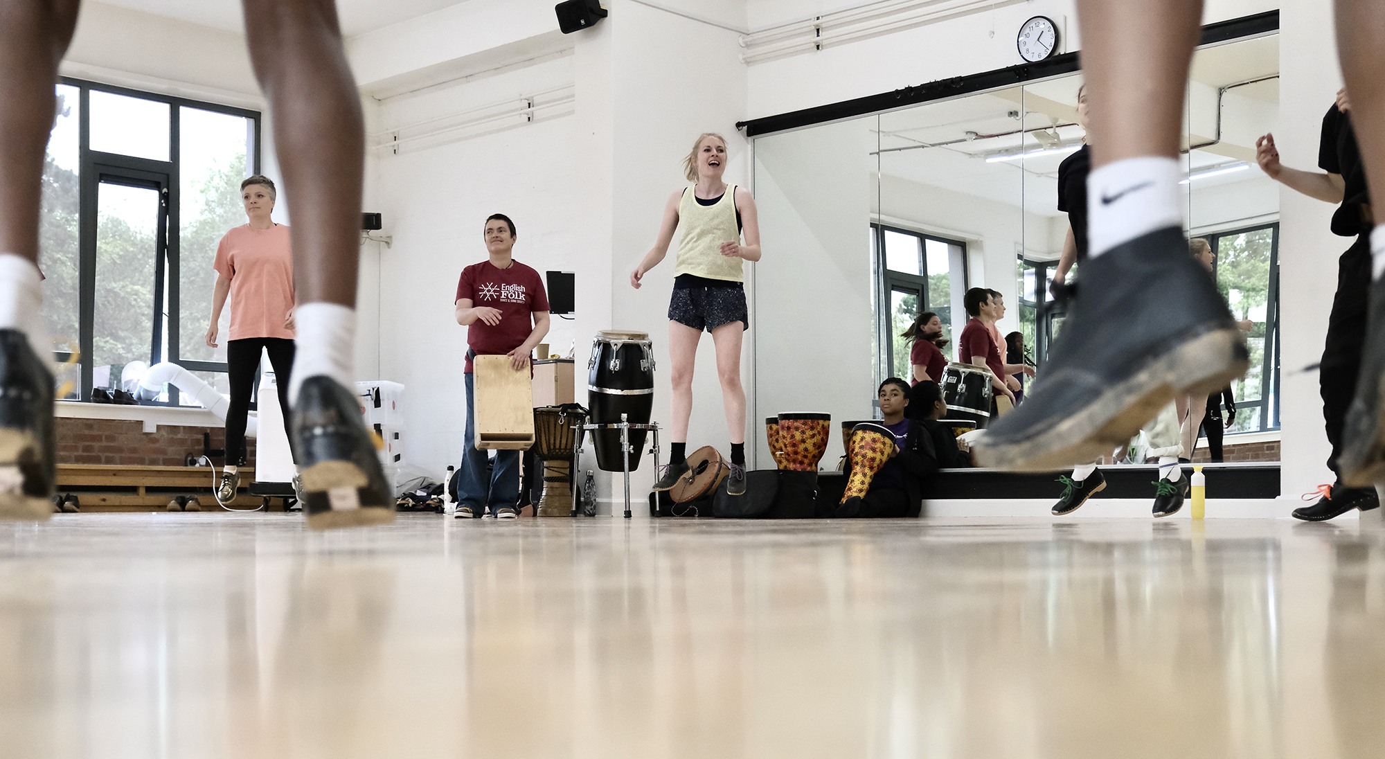 class of young people all wearing tap shoes, jumping feet in the forground jumping teacher in the background  class of young people all wearing tap shoes, jumping feet in the forground jumping teacher in the background
