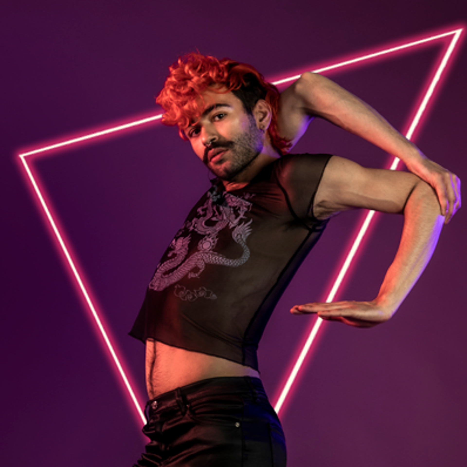 LGBTQ+ voguing dancer with curly red mohawk and black beard, holding onto his elbow. Wearing see-through black top on purple photo backdrop. LGBTQ+ voguing dancer with curly red mohawk and black beard, holding onto his elbow. Wearing see-through black top on purple photo backdrop.