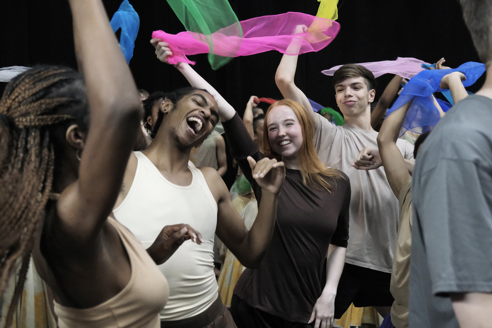 young people mixed genders and races dancing together with big smiling faced waving brightly colour scarfs. young people mixed genders and races dancing together with big smiling faced waving brightly colour scarfs.