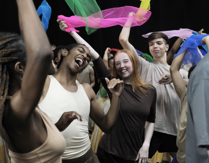 young people mixed genders and races dancing together with big smiling faced waving brightly colour scarfs. young people mixed genders and races dancing together with big smiling faced waving brightly colour scarfs.