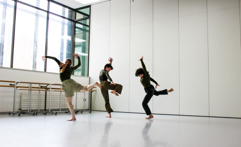 three people dancing in a dance studio with large white walls and large windows 