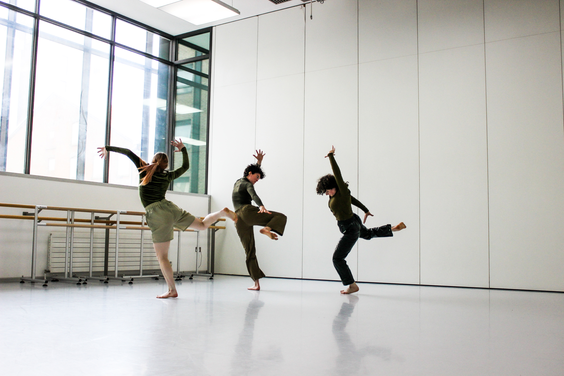 three people dancing in a dance studio with large white walls and large windows three people dancing in a dance studio with large white walls and large windows
